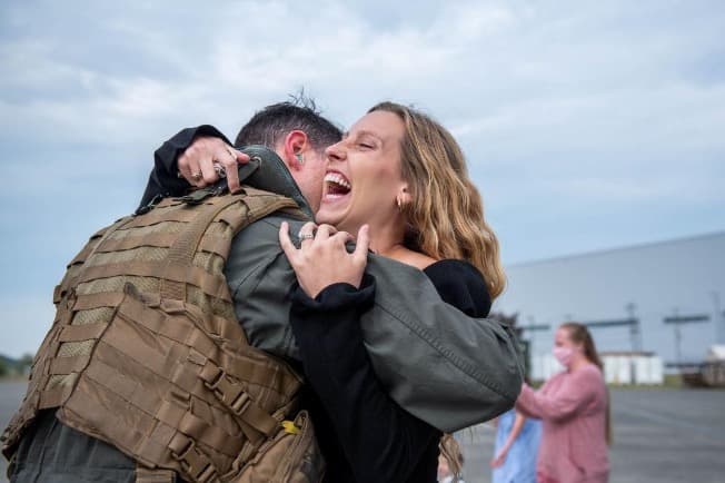 Zach Rodriguez and his wife Dani embracing at a Navy homecoming on the flight line